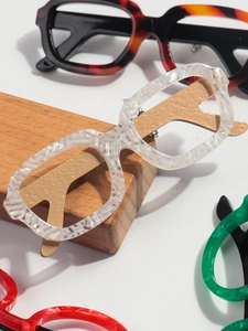 Detail of eyeglass-shaped brooches featuring ice crack patterns and golden metal arms