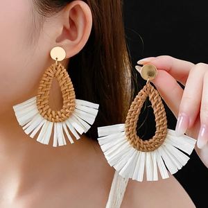 Detail of raffia drop earrings with brown teardrop weave and white fan fringes