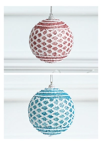 Close-up of glittery red and blue Christmas balls with white lace patterns and silver caps