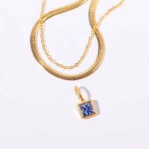 Detail view of gold layered snake chain necklace with square blue cubic zirconia pendant