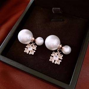 Detail of rose gold double pearl earrings with zircon flower pendant in a gift box
