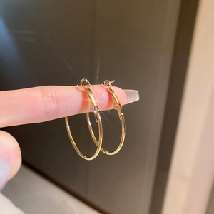 Gros plan détaillé d'une main tenant une boucle d'oreille créole dorée et polie