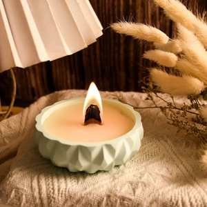 Detailed view of burning candle with wooden wick in a mint green geometric silicone mold