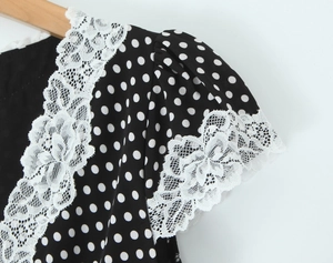 Détail du tissu à pois avec une bordure délicate en dentelle blanche sur l'épaule