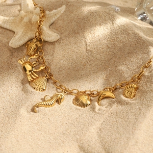 Collier en acier titane doré avec breloques marines sur fond de plage ensoleillée