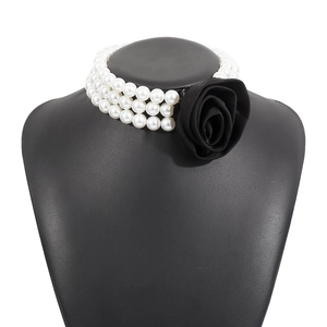 Detailed view of elegant three-layer pearl necklace with a large black fabric rose floral