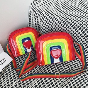 Detail of colorful rainbow crossbody bag with heart appliqué and striped webbing strap