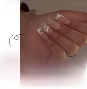 Detail of French style press-on nails with white flowers and sparkling rhinestones