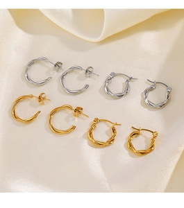 Dettaglio di orecchini a cerchio intrecciati oro e argento su seta color champagne