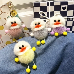 Cute plush duck keychains in pink, grey, purple and yellow on denim background