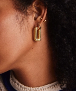 Close-up of model wearing textured 18K gold rectangular U-shaped hoop earrings