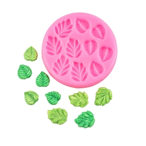 Pink silicone fondant mold for leaf shapes with green decorative icing foliage pieces