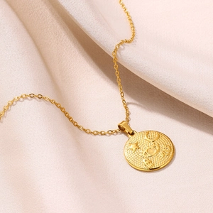 Détail d'un pendentif doré avec symboles lune et étoile sur tissu en soie beige