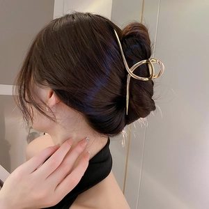 Detailed view of a golden irregular geometric metal hair claw clip worn on hair