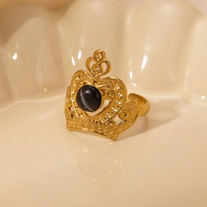 Detailed close-up of golden crown ring with grey cat eye stone on ceramic background