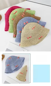 Détail de chapeaux de paille pliables colorés avec des nœuds roses contrastés