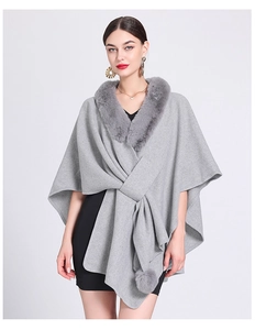Detailed close-up of grey knitted poncho featuring thick faux rabbit fur collar trim