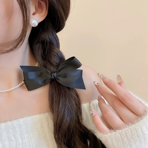 Pince à cheveux élégante en satin noir sur une tresse pour un look chic à la française