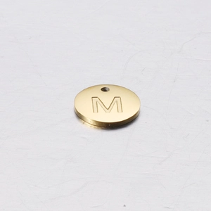 Detailed close-up of a 12mm golden stainless steel round pendant with engraved letter M