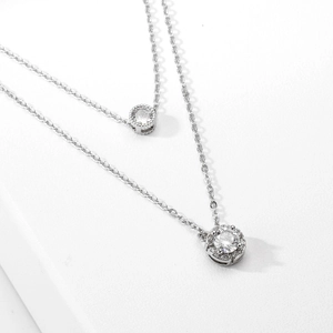 Double layer silver necklace with white cubic zirconia pendants on white platform