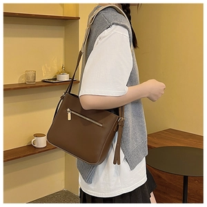 Detail of dark brown bucket bag with textured shoulder strap and gold zipper pocket