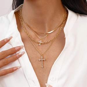 Detail of layered gold necklaces with cross pendants and sparkling rhinestones on model