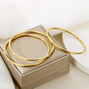 Three-piece stackable 18K gold plated minimalist round bangles on a luxury jewelry box