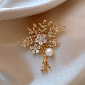 Detailed view of a gold floral brooch with sparkling zircons and a large central pearl