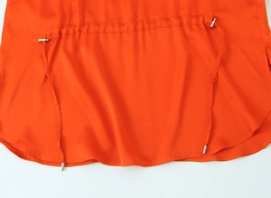 Detailed macro view of orange satin fabric texture with metallic drawstring toggle