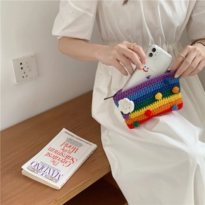 Detail of handmade crochet rainbow bag with colorful pom-poms and 3D floral accent