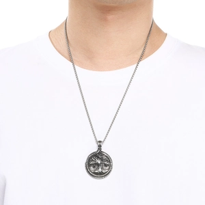 Detail of vintage silver Viking Tree of Life pendant worn by a male model on a white shirt