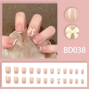 Close-up of French tip press-on nails with 3D yellow bows and glossy nude base