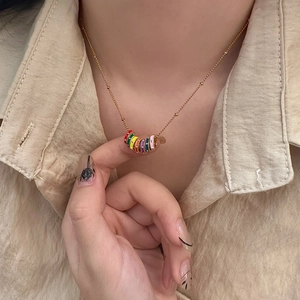 Close-up of a golden necklace featuring a vibrant multi-colored enamel circle pendant