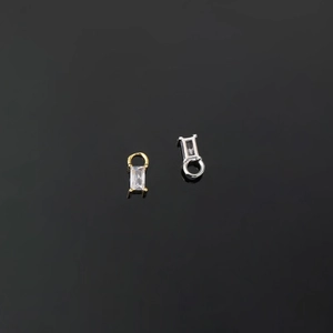 Detailed macro view of gold and silver charms featuring rectangular cubic zirconia stones
