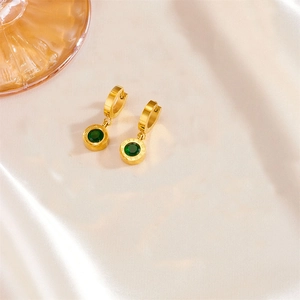 Detail of gold roman numeral earrings with green gemstone on elegant silk background