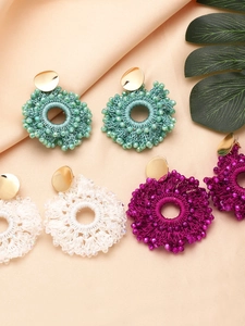 Flat lay of colorful bohemian beaded earrings in green, white and pink on silk fabric