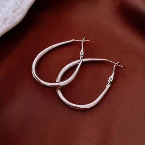 Detailed view of silver oval hoop earrings on elegant dark satin with smooth metal finish