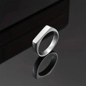 Polished silver stainless steel signet ring with flat top on dark reflective background