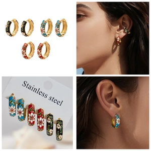 Detail view of colorful floral enamel stainless steel hoop earrings in gold finish