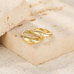 Close-up of gold-plated silver wave hoop earrings with inlaid zircons on stone