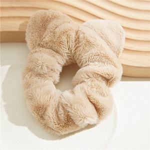 Detail of plush khaki scrunchie with cute bear ears on a white decorative plate