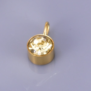 Detail of a golden stainless steel pendant featuring a large faceted yellow gemstone