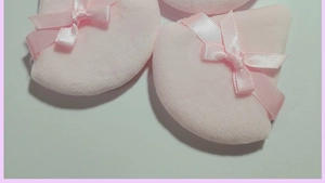 Close-up of pink triangular velvet powder puffs featuring decorative silk ribbon bows