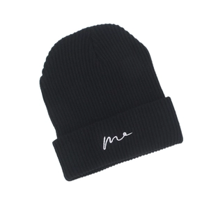 Detailed close-up of ribbed texture and me embroidery on black knit beanie