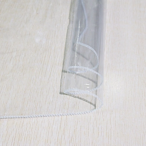 Waterproof transparent PVC tablecloth with white stitched edges on light wood surface