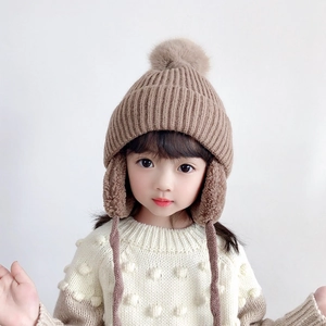 Brown knit children earflap hat with fluffy pom-pom and warm fleece lining for winter
