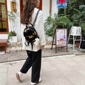 Vue détaillée d'un sac à dos en peluche léopard avec un porte-clé d'ours blanc mignon attaché