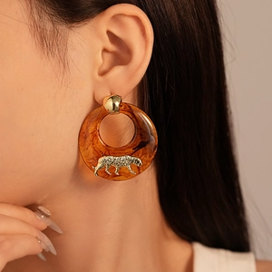 Close-up of resin amber hoop earring with a golden leopard ornament on a model
