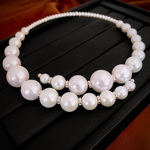 Detailed close-up of oversized faux pearls with silver spacers on a textured jewelry tray