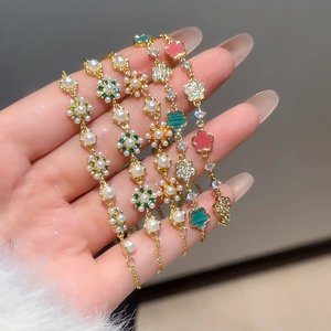 Elegante verstellbare Goldarmbänder mit Perlen und farbenfrohen Emaille-Blumenanhängern